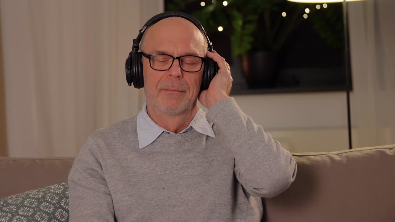 old man in headphones listening to music at home