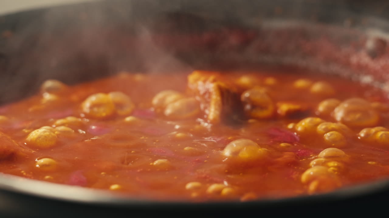 Chicken in tomato sauce is boiling on a frying pan with spices. Cooking tomato sauce curry with chicken fillet. Traditional Italian Mexican Asian dish. High quality studio shot for cafe, restaurant close up.