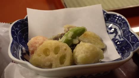 traditional japanese vegetarian food with tofu and lotus, served in a small porcelain bowl on a red dinner tray