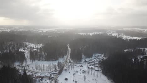 Muy-Por-Encima-De-Un-Pequeño-Pueblo-De-Invierno-Con-Luz-Solar-Empujando-A-Través-De-Las-Nubes-Y-Nieve-Ligera-En-El-Aire