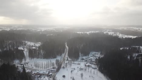 high above a small winter town with sun light pushing trough the clouds and light snow in the air