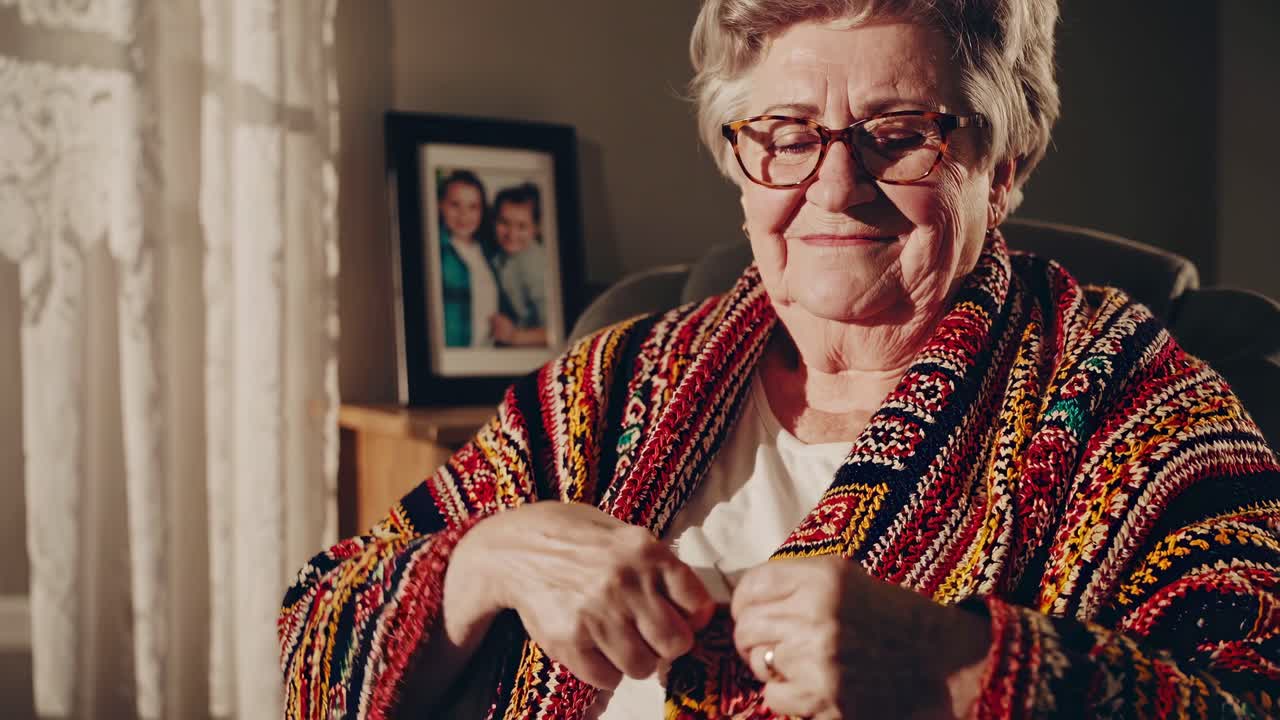 Warm, nostalgic video scene of an elderly woman knitting in a cozy room, captured from a side angle