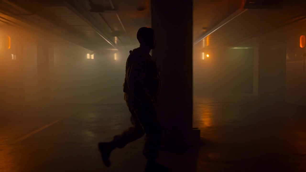 A lone man in silhouette walks across a shadowy underground corridor with warm orange backlight, concrete columns, haze, and reflective surfaces creating a