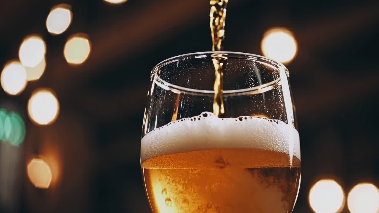 Nahaufnahme eines Videos, in dem Bier in ein Glas gegossen wird, aufgenommen aus einem niedrigen Winkel