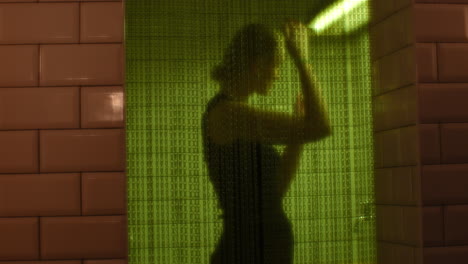 silhouette behind a green lit translucent partition