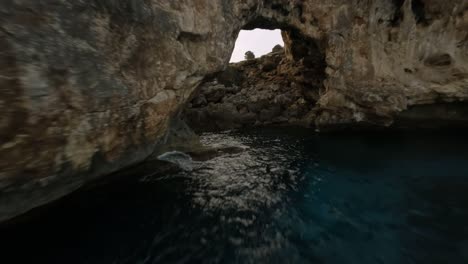 fpv drone disparó mientras volaba de un arco de roca natural a lo largo de la orilla del mar en cala varques, mallorca, españa durante la noche