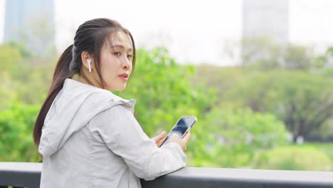 4k asian woman listening to music while jogging at public park in the morning.