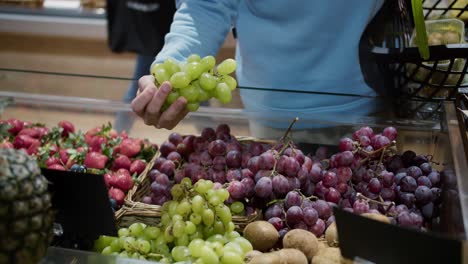 Mano-Masculina-Eligiendo-Uvas-En-El-Supermercado,-Poniendo-A-La-Cesta