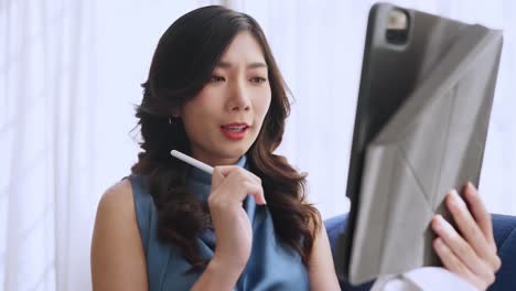 casual working at home relax casual using tablet device in living room,asian female adult hand typing search or texting via laptop sofa working from home with happiness peaceful smiling ideas concept