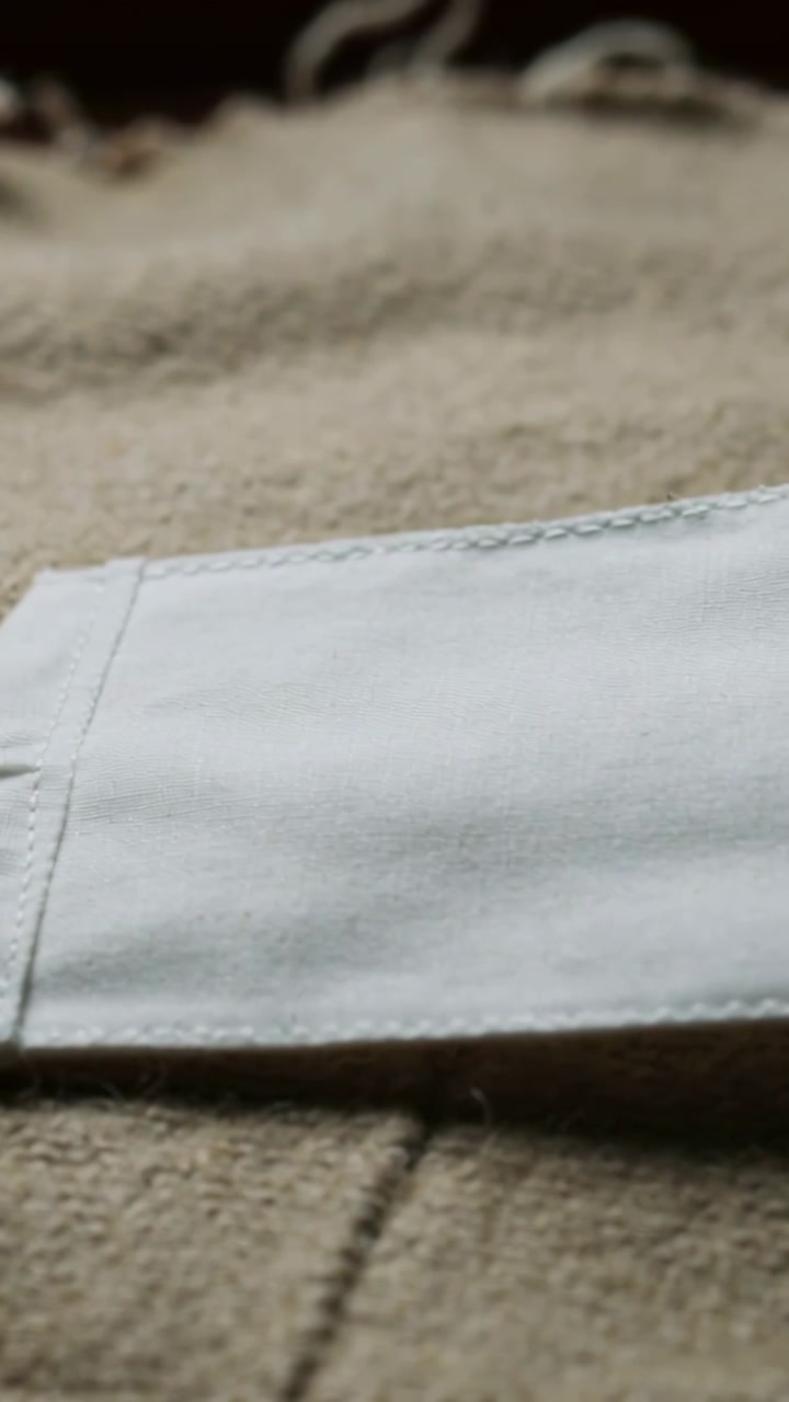 White cloth piece with elastic loop sliding right after tug on beige blanket, revealing stain