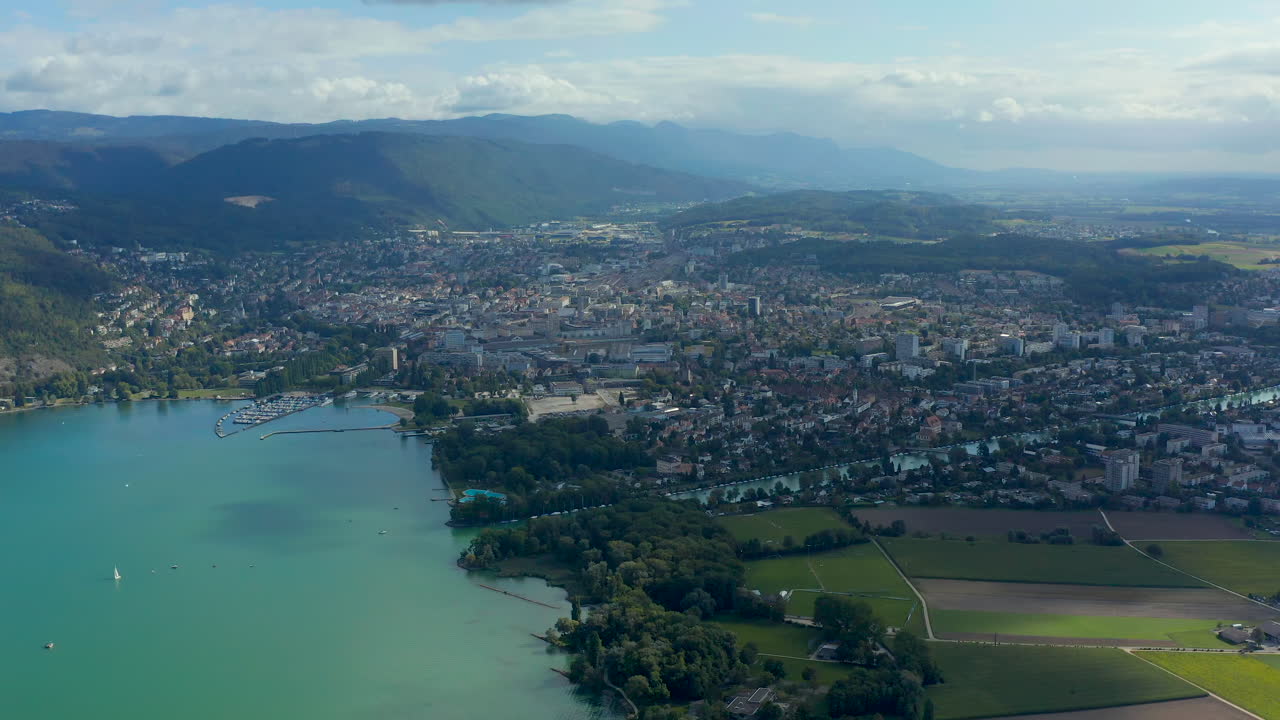 Aerial view of 'Lake Biel' and the city Biel and the Nidau-Büren Canal with clear greenish-blue water surrounded by a scenic landscape on a sunny day under blue sky with fluffy clouds CH