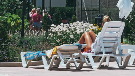 personas sentadas a la orilla de la piscina de un resort durante las vacaciones de verano