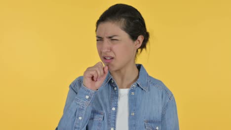 sick young indian woman coughing, yellow background