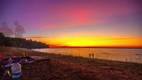 puesta de sol colorida sobre una playa serena con personas empacando después de un picnic, timelapse