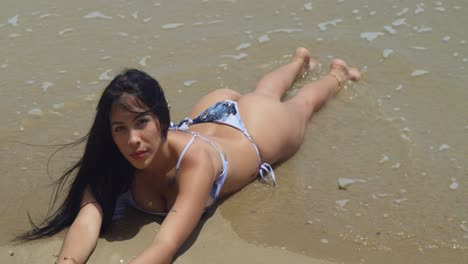 a sunny day finds a young girl in a bikini exploring the sandy expanse of a tropical island beach laying in the water