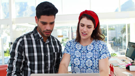 Male-and-female-executives-discussing-over-laptop-at-desk-4k