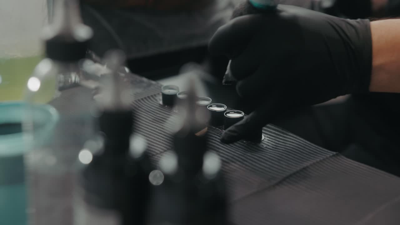 A Tattoo Artist Dips the Needle Into a Small Ink Cup, Ready to Work - Close Up