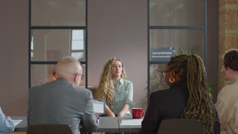 caucasian woman speaking with hiring committee on job interview