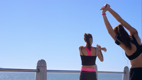 Two-athletic-friends-stretching-on-promenade-before-run