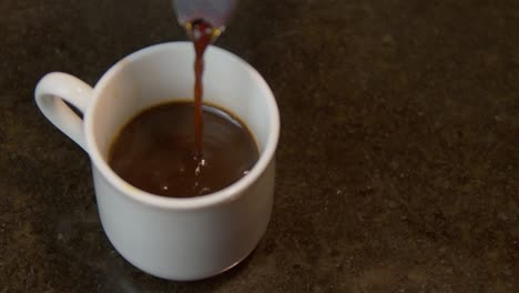 pouring hot coffee on the white cup from moka pot-closeup shot