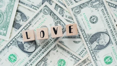 rotating word love from wooden letters, on dollars, concept