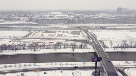 Aerial-dolly-left-shot-cars-driving-onto-a-highway-during-a-snowstorm-in-Montreal-Canada