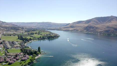 drone flying over houses towards lake and mountains