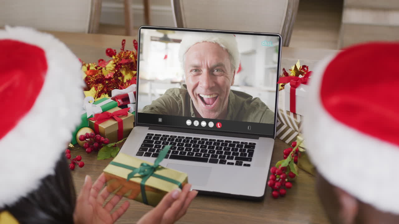 산타 모자를 입은 다양한 커플이 행복한 백인 남자와 노트북 비디오 통화를 하고 있습니다.