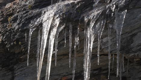 Ein-Zartes-Gitter-Aus-Eiszapfen-Hängt-An-Den-Dunklen-Felsen