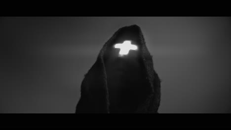 masked man with cross of light glowing on his face moves his head up
