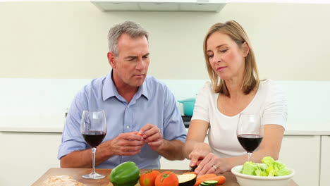 mature couple drinking red wine together and making a salad