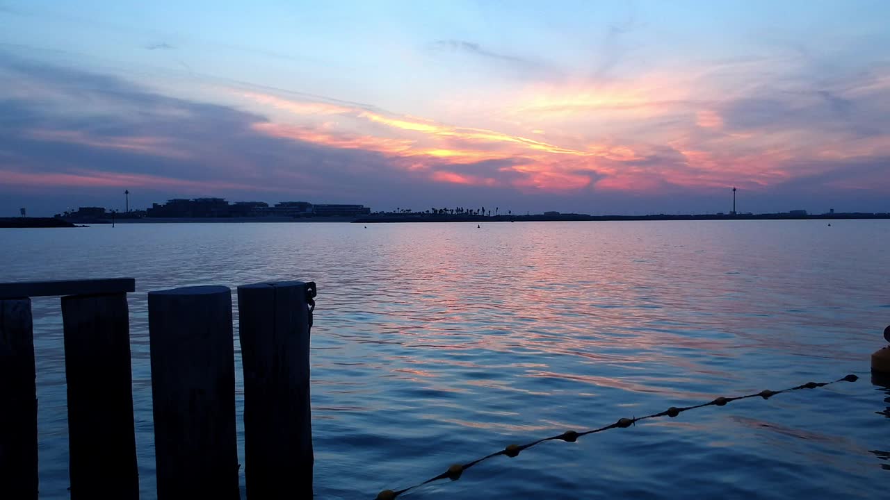 두바이 주메이라의 잔잔한 해안 위로 다채로운 일몰을 감상할 수 있는 편안한 드론 뷰