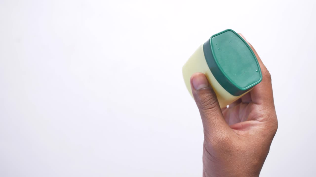 Top view of man hand holding a petroleum jelly container ,