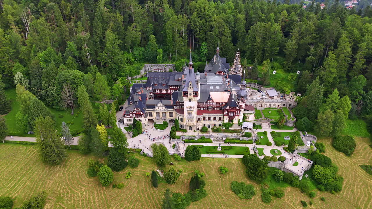 Fantastisk nyrenessansepalass i det kongelige området Sinaia i Karpatene, nær Sinaia, i Prahova fylke, Romania. Mange mennesker går forbi området. Luftfoto