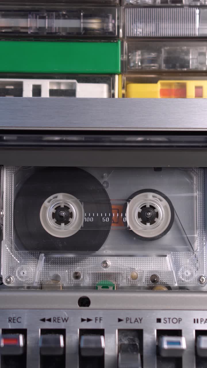 vista vertical de cinta de cassette de audio tocando en la cubierta con un montón de cassettes en la parte superior, grabaciones antiguas de las décadas de 1970 y 1980