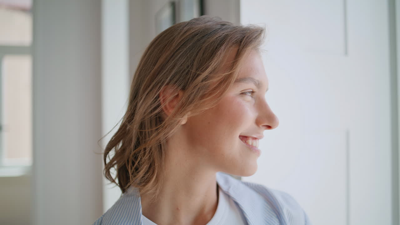 Ritratto di una donna sorridente in una stanza luminosa. Ragazza felice che posa sognante al mattino
