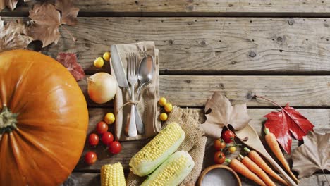 múltiples ingredientes alimentarios, hojas de otoño y cubiertos con espacio de copia en superficie de madera