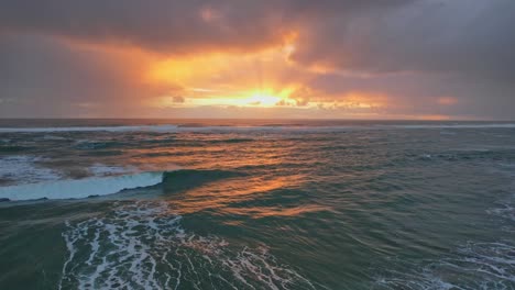 golden sunset with gray cloudy skies over tasman sea at piha beach in auckland, new zealand