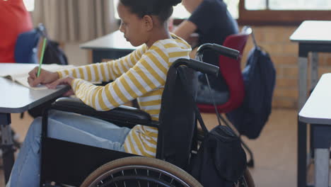 in school, girl in wheelchair writing in notebook, concentrating on work