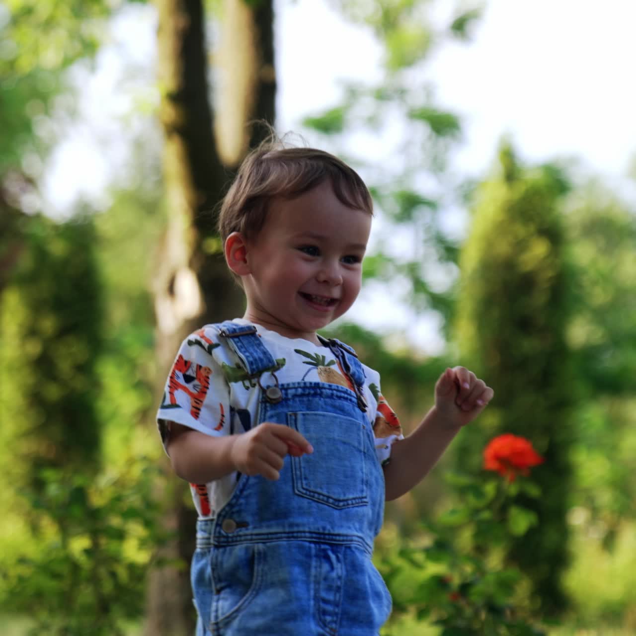 Criança feliz e sorridente com uma bola correndo no parque. Bebê ativo joga a bola na estrada