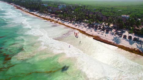 Vista-Aérea-De-Drones-De-Niños-Volando-Cometa-De-Playa-De-Paracaídas-En-Una-Playa-Caribeña-Tropical