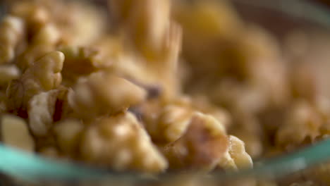 slow motion footage of walnut pieces falling into a dish