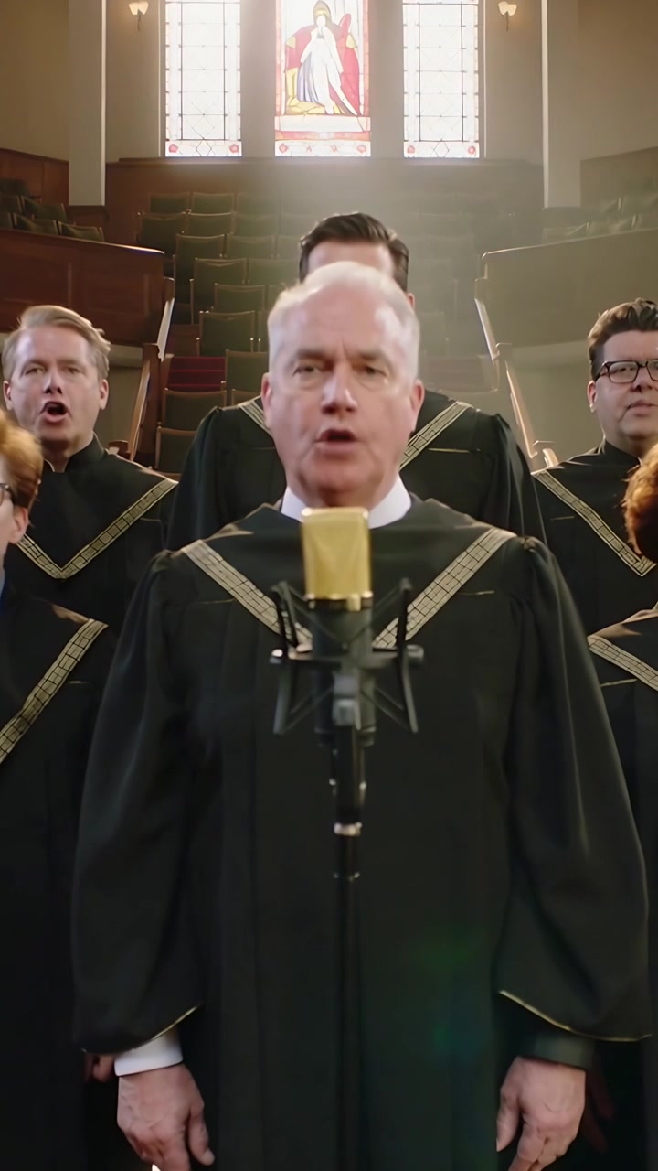Video verticale: Inspirando, direttore del coro in tonaca che canta in un microfono dorato in chiesa, guidando l'armonia.