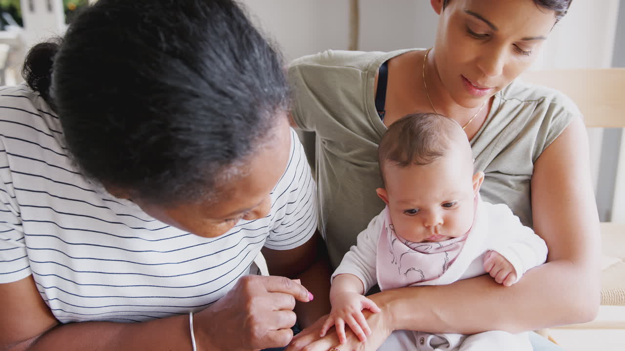 어머니 와 딸 이 집 에서 의자 에 앉아 있는 아기 손녀 를 안고 있다