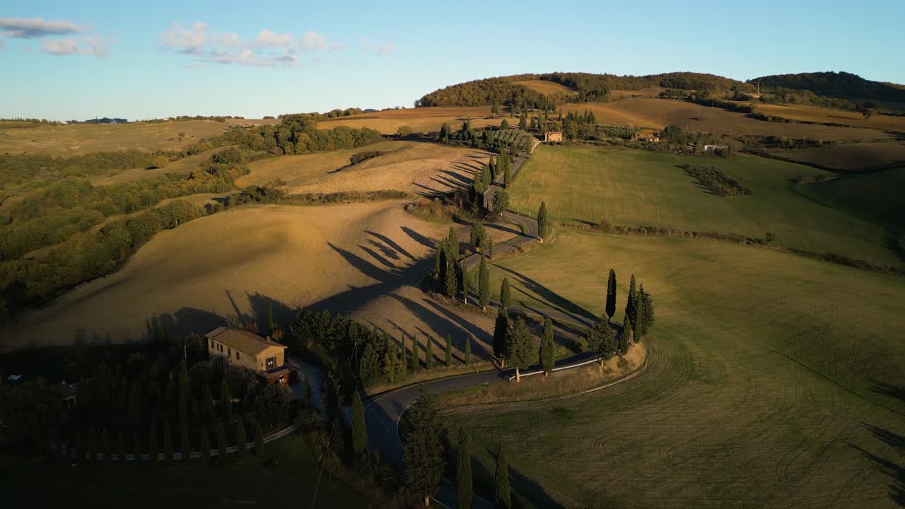 드론은 토스카나 시골의 그림자에 의해 황금 빛나는 풀 언덕에 내려갑니다.