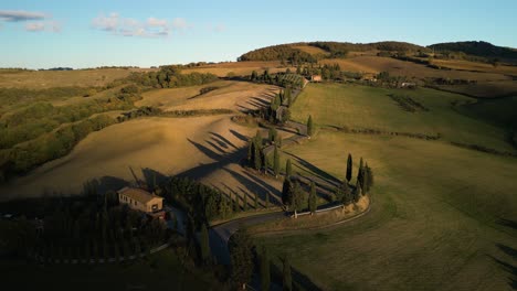 drone descends on golden glowing grass hills by shadows of tuscan countryside