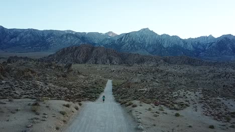 aerial slowmotion view on lonely male running on desert road in twilight, alabama hills, california usa