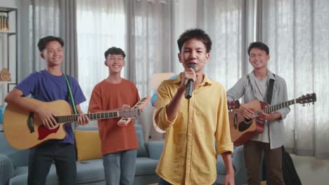 group of young asian friends with musical instruments waving hand and speaking at home