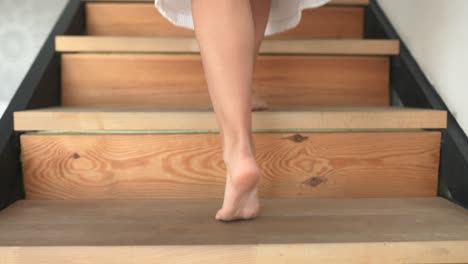 Child walking barefoot up wooden stairs