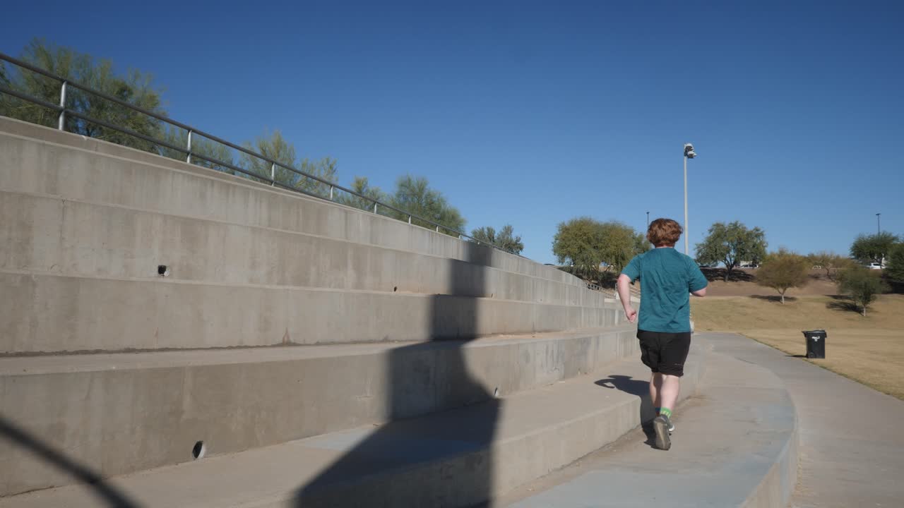 un hombre pelirrojo gordo corre en zigzags por el cemento en un parque.